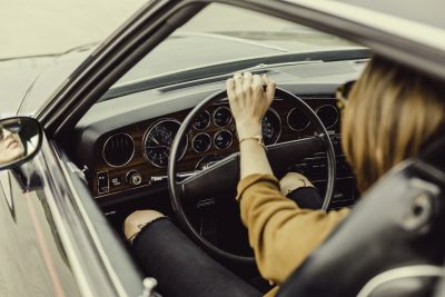 Imagen de chica conduciendo un coche antiguo.