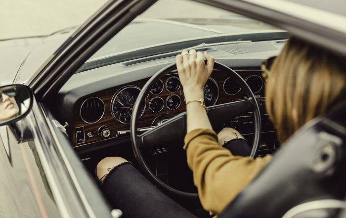 Imagen de chica conduciendo un coche antiguo.